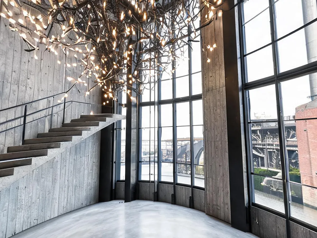 Concrete museum atrium with a light sculpture and a floating staircase